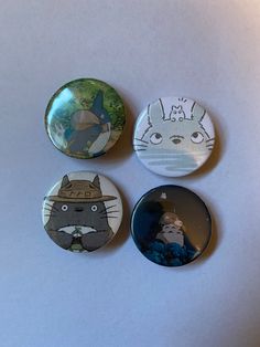 three buttons with cartoon characters on them sitting on a white surface in front of a wall