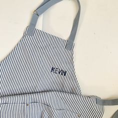 an apron with the name kenn on it sitting next to scissors and a pair of scissors