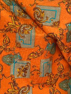 an orange and blue paisley print fabric with square shapes on the center, surrounded by smaller squares