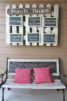 a bench sitting in front of a wall with signs on it and two red pillows