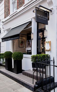 the entrance to an upscale restaurant with black iron railings and potted plants outside