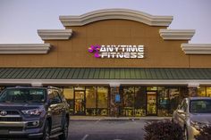 two cars are parked in front of an anytime fitness store