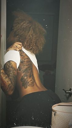 a woman with tattoos on her back standing in front of a toilet