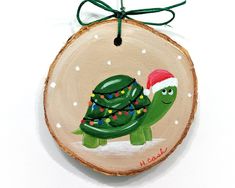 a wooden ornament with a green turtle wearing a santa hat and lights on it