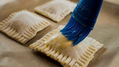 a person is using a blue brush to make empanada pies look like they're from the past