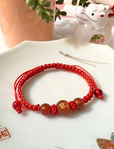 a red string bracelet sitting on top of a table next to a potted plant