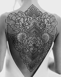 the back of a woman's body with an intricate tattoo design on her shoulder