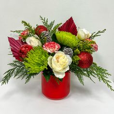 a red vase filled with flowers and greenery