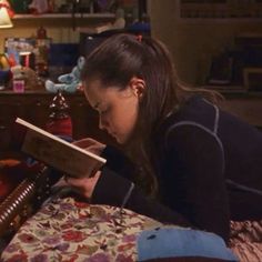 a girl is reading a book on her bed