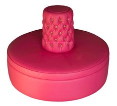 a pink hat sitting on top of a round box with gold studded decorations around it