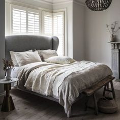 a bed sitting in a bedroom next to a window with shutters on the windowsill