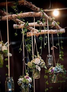 an arrangement of flowers hanging from a tree branch