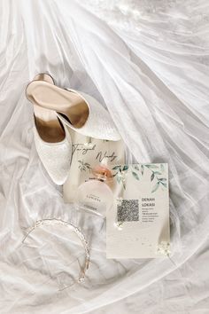 a pair of white shoes sitting on top of a bed next to a wedding ring