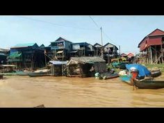 there are many boats in the water near some houses and shacks on stilts