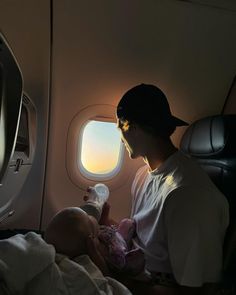 a man holding a baby while looking out an airplane window