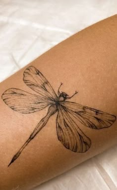 a black and white photo of a dragonfly tattoo on the right arm, it appears to be inked