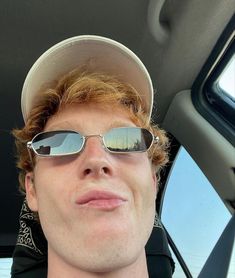 a man wearing sunglasses and a hat sitting in a car