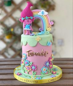 there is a cake decorated with flowers and a pink troll on the top that says tamer