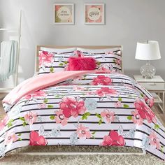 a bed with pink flowers on it in a white and black room next to a lamp