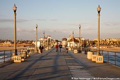 people are walking on the pier near the water and some light poles with lamps hanging above them