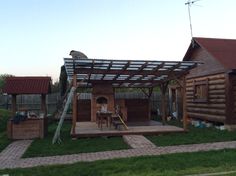 a wooden house with a covered patio and picnic table in the back yard, surrounded by grass