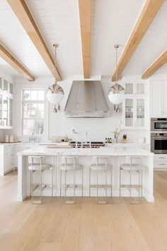 a large kitchen with white cabinets and wooden beams on the ceiling is pictured in this image