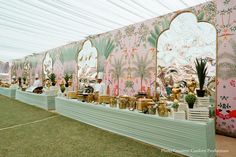 a long table with vases and plants on it in front of a colorful wall