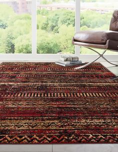 a living room area with a large rug on the floor and a chair in front of it