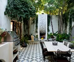 an outdoor dining area with black and white tile flooring, potted plants and trees