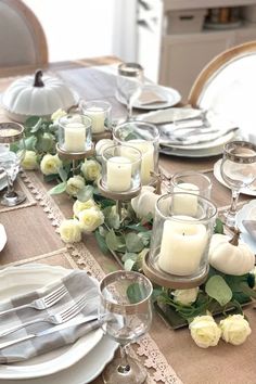 the table is set with silverware, candles and white flowers on top of it