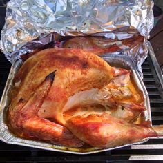 a roasted chicken is sitting on top of an aluminum foil covered bbq grill, ready to be cooked