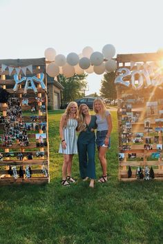 three women standing next to each other in front of wooden crates with photos on them