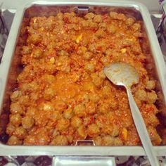 a casserole dish with meat in it and a spoon resting on the side