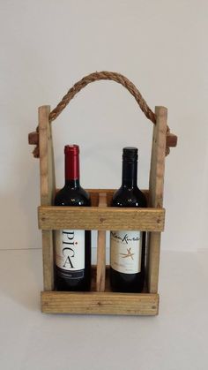 two bottles of wine sit in a wooden crate with rope handles on the top and bottom