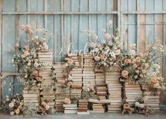 an arrangement of books and flowers are arranged in front of a wall made out of wooden pallets