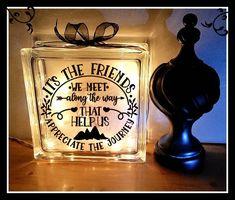 a glass block with a quote on it next to a candle holder that says, friends we meet among the ways that help us celebrate the journey