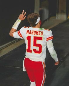 a man in a football uniform is walking down the street with his hand raised up