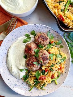 some meatballs and pasta on a white plate with sauce in a bowl next to it