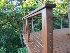 a wooden deck with metal railing and trees in the background