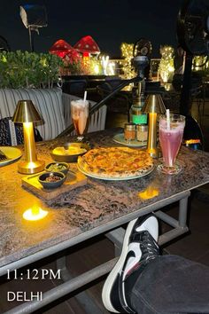 a table with food and drinks on it at an outdoor restaurant in the evening time