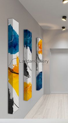 three abstract paintings hang on the wall next to a white door in an empty room