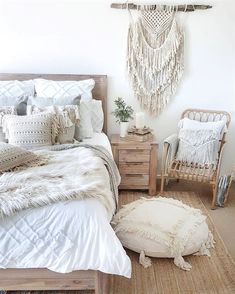 a bedroom with white bedding, pillows and rugs on the floor next to a chair