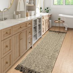 a bathroom with wooden cabinets and a rug on the floor in front of the bathtub