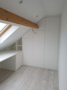 an empty room with white walls and wood flooring in the corner, under a slanted roof