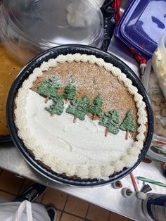 a cake with frosting and trees on it sitting on a table next to other food