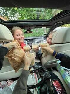 two women sitting in the back seat of a car drinking coffee and talking to each other