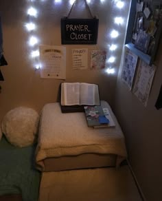 a small bed with a book on top of it and some lights above the headboard