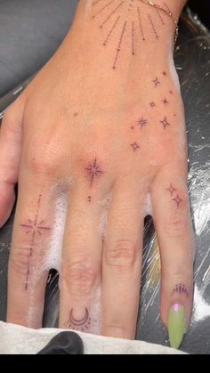 a woman's hand with stars and moon tattoos on it