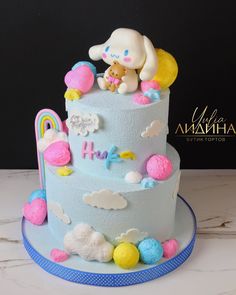 there is a blue cake decorated with clouds and a teddy bear on the top tier