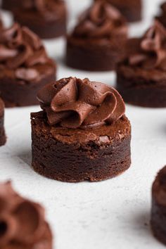 chocolate cupcakes with frosting sitting on top of a white surface, ready to be eaten